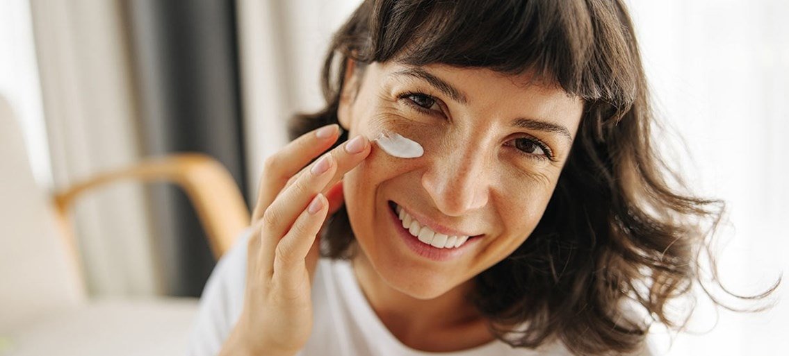 Vrouw smeert huidverzorgingsproduct op gezicht